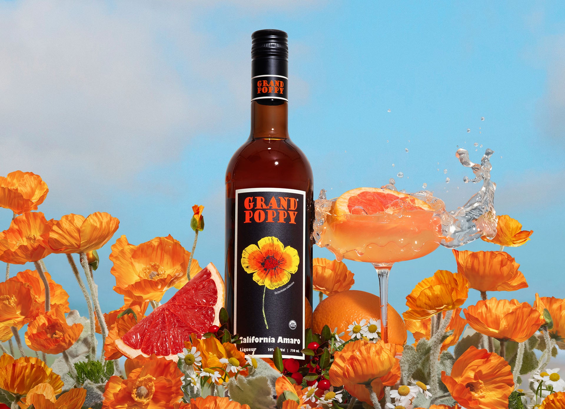 Bottle of Grand Poppy California Amaro with grapefruit and flowers on a blue sky background